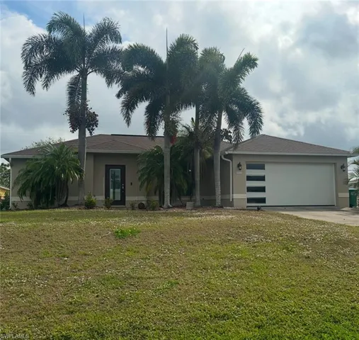 View of front of home featuring a front lawn, stucco siding, an attached garage, and concrete driveway