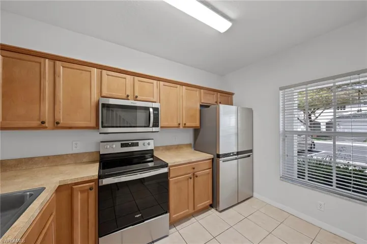 Kitchen with stainless steel appliances, light countertops, and light tile patterned floors