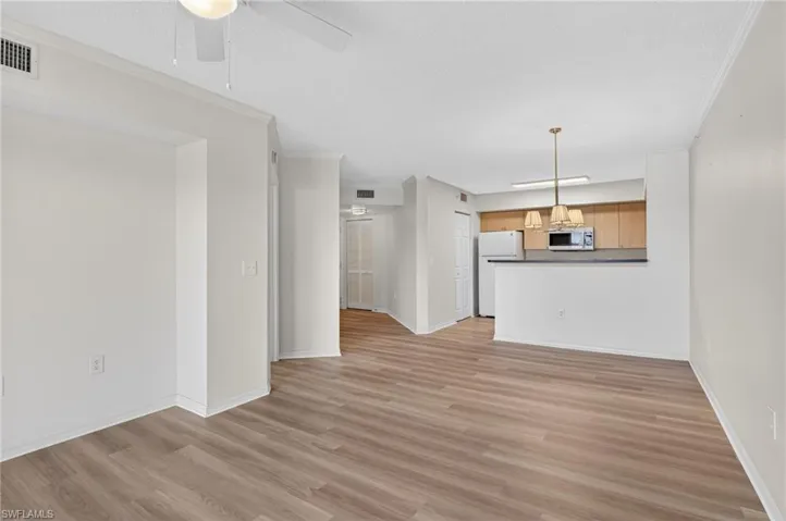 Unfurnished living room with crown molding, light wood-style flooring, and a ceiling fan