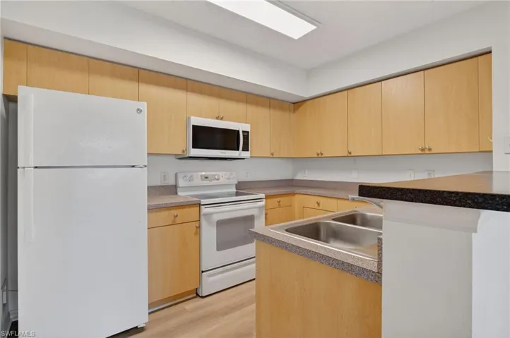 Kitchen with white appliances and light wood finish cabinetry