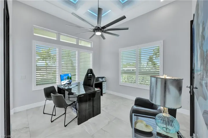 Office with coffered ceiling, plenty of natural light, ceiling fan, and beam ceiling
