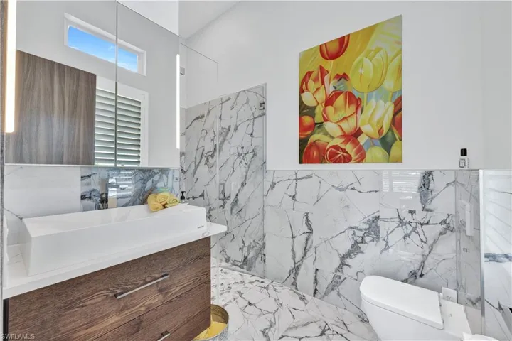Full bathroom with vanity, a marble finish shower, marble tiled floors, and tile walls