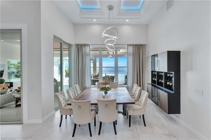 Dining room with a chandelier, a towering ceiling, a water view, and recessed lighting