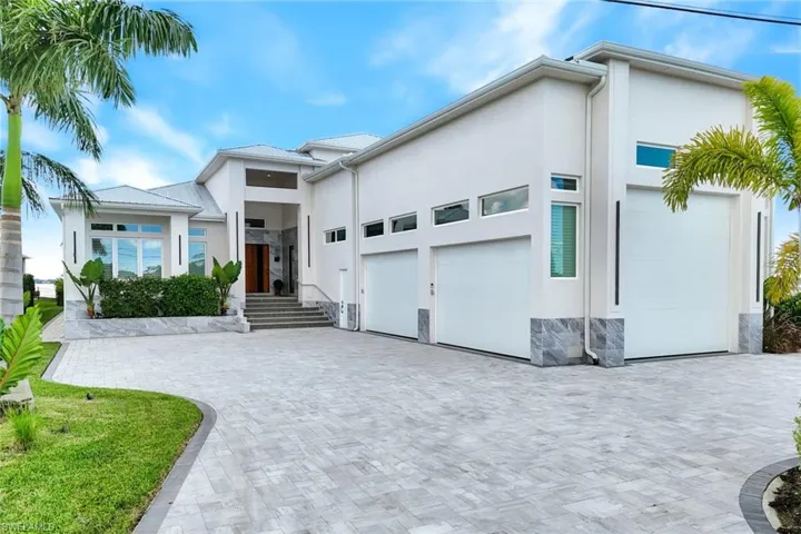 View of front facade featuring stone siding, stucco siding, a garage, and decorative driveway