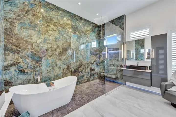 Bathroom with vanity, a freestanding tub, a marble finish shower, marble tiled flooring, and tile walls