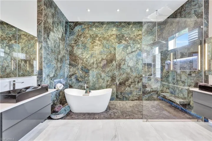 Master Bathroom featuring vanity, tile walls, a marble finish shower, a freestanding bath, and marble tiled floors