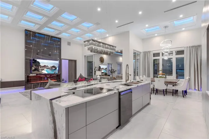 Kitchen featuring modern cabinets, a high ceiling, a chandelier, a center island with sink, and hanging light fixtures