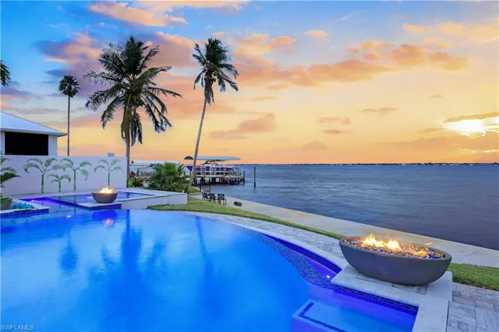 Outdoor pool with an outdoor fire pit, a hot tub, and a water view