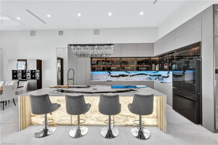 Kitchen with modern cabinets, a spacious island, black fridge, a breakfast bar, and gray cabinets