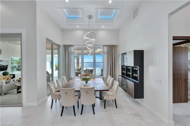 Dining area with a chandelier, a water view, recessed lighting, and a towering ceiling