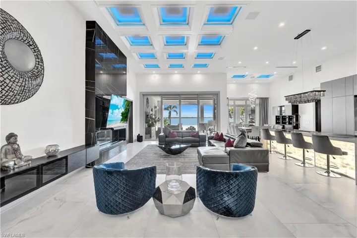 Living room featuring a high ceiling, light marble finish floors, recessed lighting, and coffered ceiling