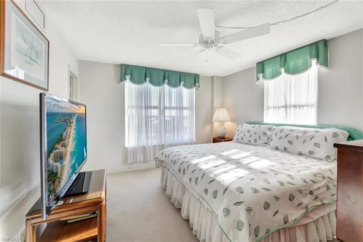 Bedroom featuring light carpet, a textured ceiling, and ceiling fan