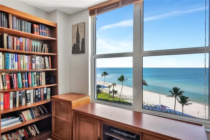Home office with a water view, a healthy amount of sunlight, a beach view, and a textured ceiling