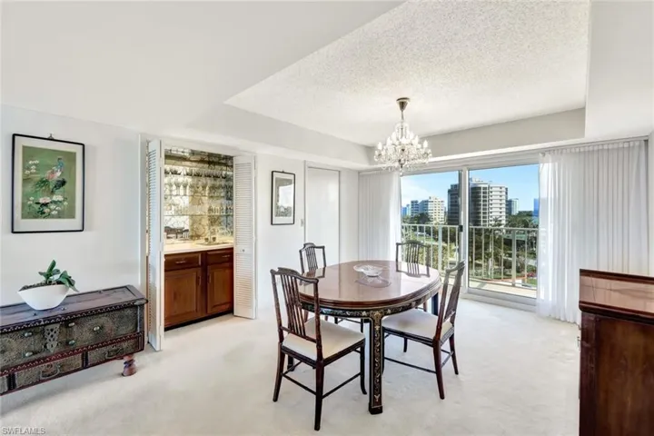 Carpeted dining area with a notable chandelier and a textured ceiling