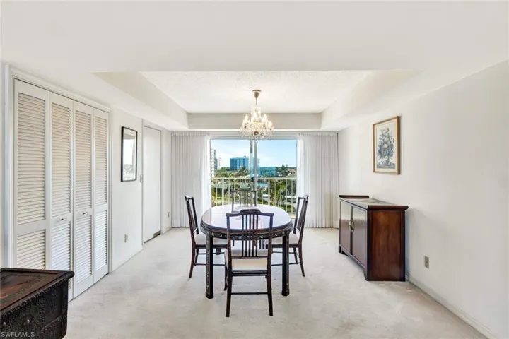 Carpeted dining room featuring a raised ceiling, a textured ceiling, and a chandelier