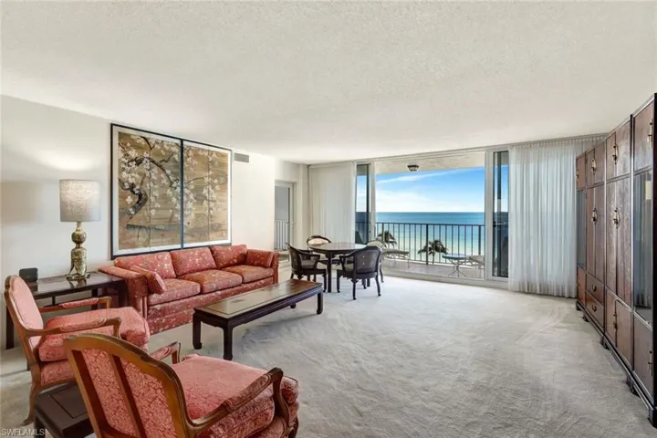 Carpeted living room with a water view, a wall of windows, and a textured ceiling