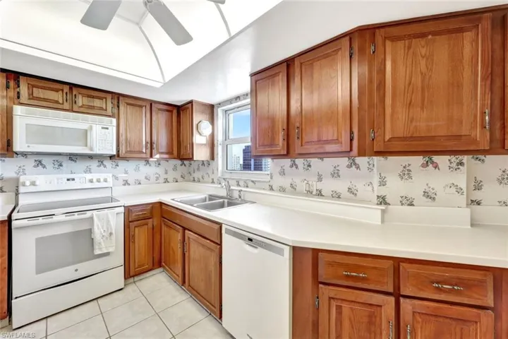 Kitchen featuring ceiling fan, sink, light tile patterned floors, and white appliances