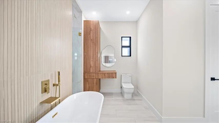 Full bathroom with a freestanding bath, vanity, and recessed lighting
