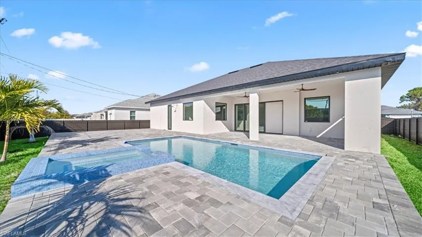 Rear view of house featuring a ceiling fan, a patio area, a fenced backyard, a pool with connected hot tub, and stucco siding