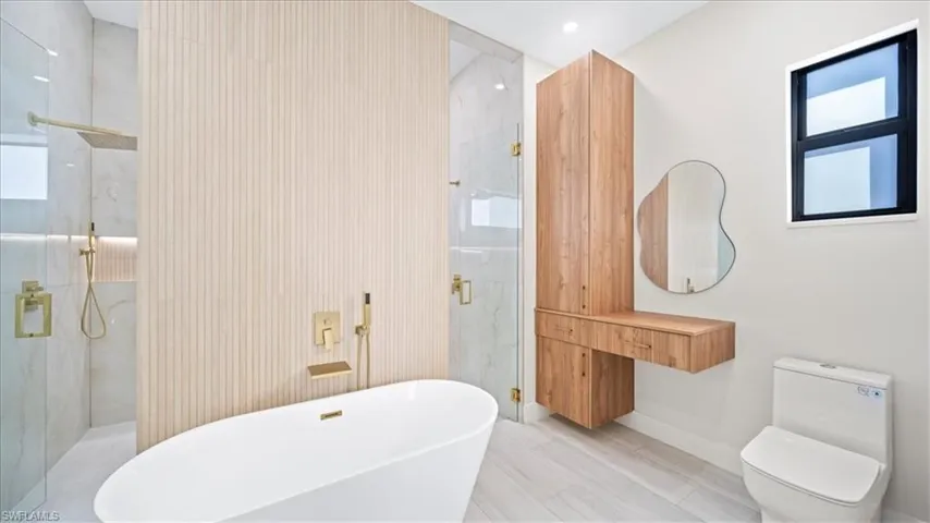 Bathroom with a marble finish shower, a soaking tub, and vanity