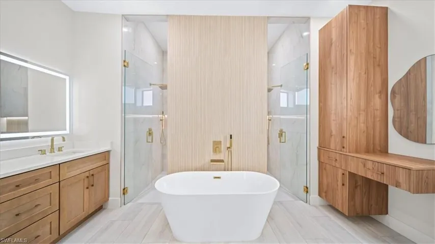 Full bath with vanity, a marble finish shower, and a freestanding bath