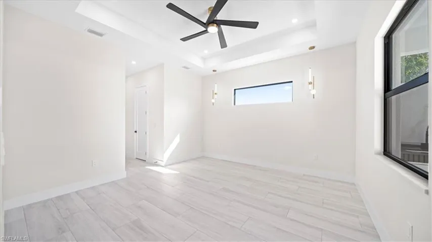Empty room featuring ceiling fan, wood tiled floors, recessed lighting, and a tray ceiling