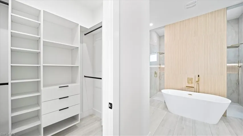 Full bathroom featuring a marble finish shower, a walk in closet, and a freestanding bath
