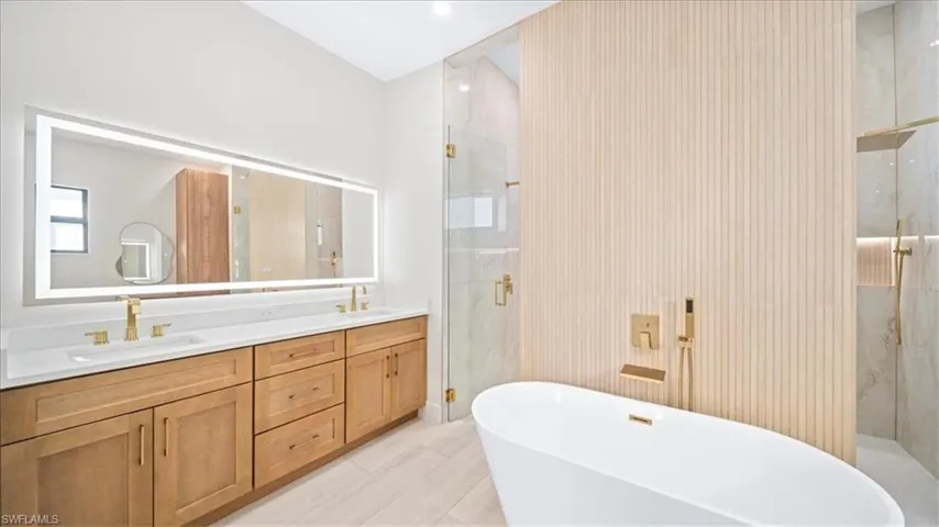 Bathroom with a marble finish shower, double vanity, and a freestanding bath