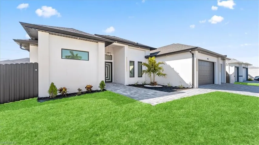 View of front of home featuring an attached garage, stucco siding, and decorative driveway