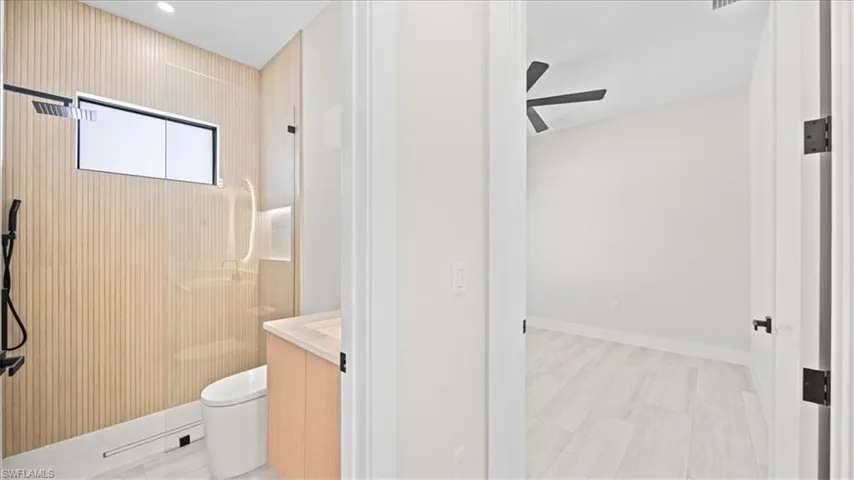 Bathroom featuring a walk in shower, vanity, and ceiling fan