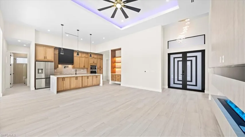 Kitchen with a large island with sink, open floor plan, stainless steel appliances, a ceiling fan, and pendant lighting