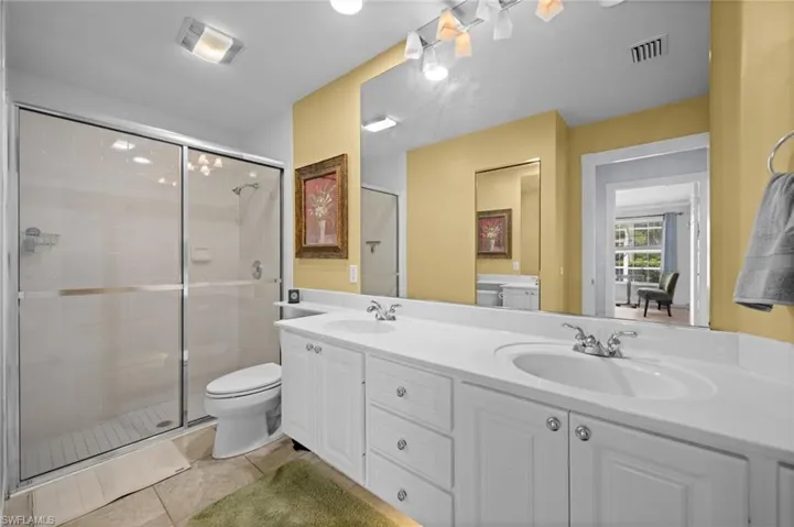 Full bathroom featuring double vanity, a shower stall, and light tile patterned floors