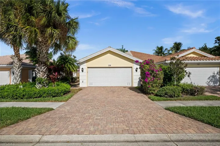 View of front of property with decorative driveway, stucco siding, a tile roof, and a garage