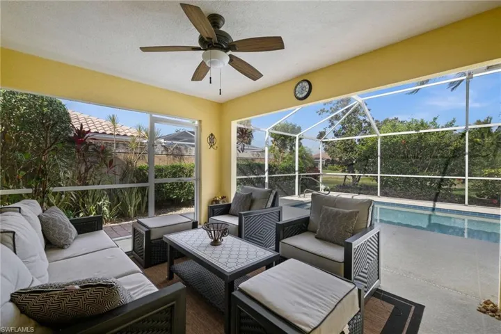 View of patio featuring glass enclosure, a sunroom, ceiling fan, and an outdoor living space