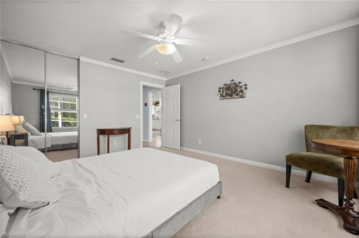 Bedroom with crown molding, light carpet, ceiling fan, and a closet