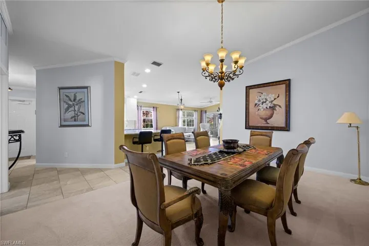 Dining space with ornamental molding, a chandelier, light carpet, light tile patterned floors, and recessed lighting