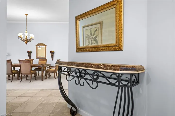 Hallway with ornamental molding and a chandelier