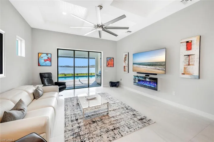 Living room featuring ceiling fan, coffered ceiling, and light tile patterned floors