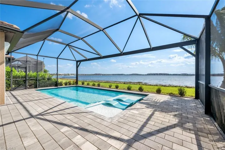 View of swimming pool featuring a patio, a water view, and glass enclosure