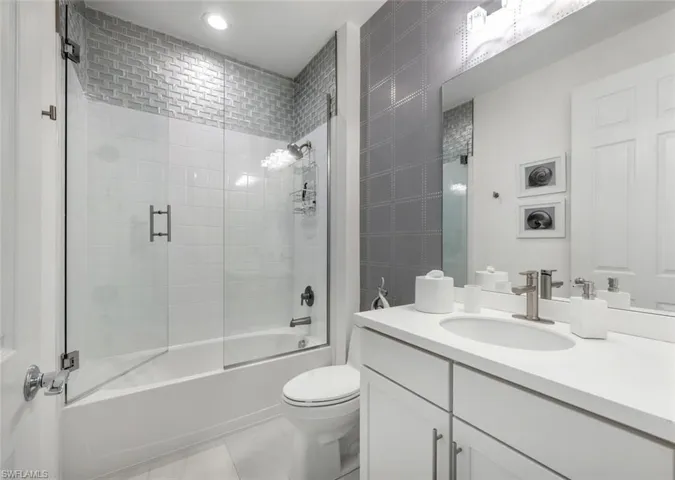 Full bathroom featuring toilet, enclosed tub / shower combo, vanity, and tile patterned floors