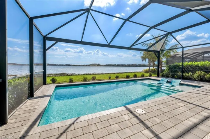 View of pool featuring a water view, a patio, and glass enclosure