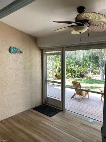 Doorway to outside featuring a textured wall, a ceiling fan, and wood finished floors
