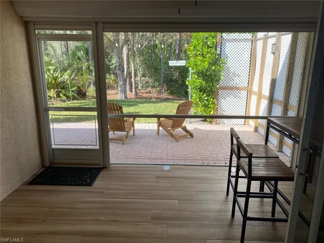 Doorway to outside featuring a textured wall, healthy amount of natural light, and wood finished floors