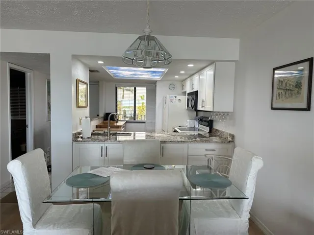 Open-concept kitchen featuring white cabinetry, granite-finish countertops, recessed lighting, and a skylight