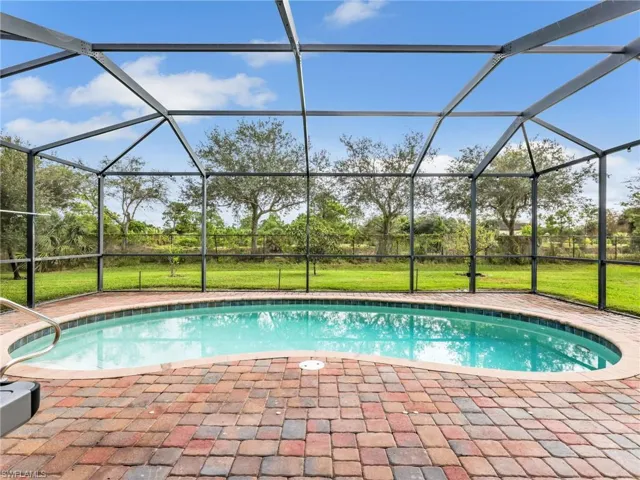 Swimming pool with a lanai, a sunroom, and a yard