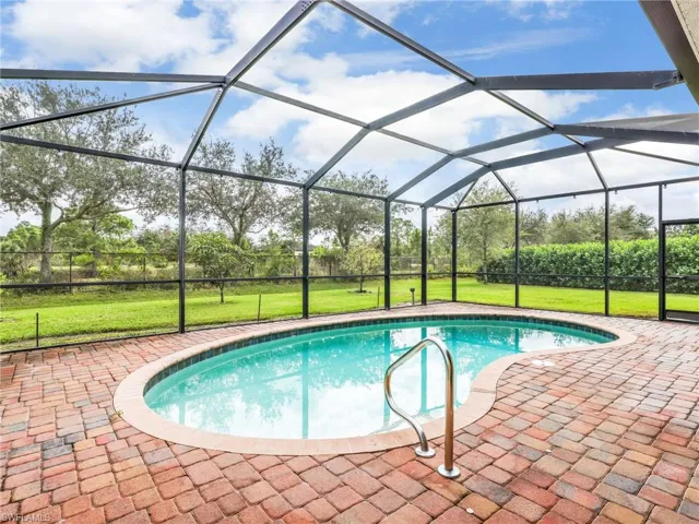Swimming pool with a lawn, a sunroom, glass enclosure, and a patio
