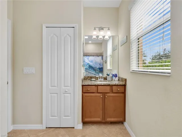 Full bath with a closet, vanity, and light tile patterned floors