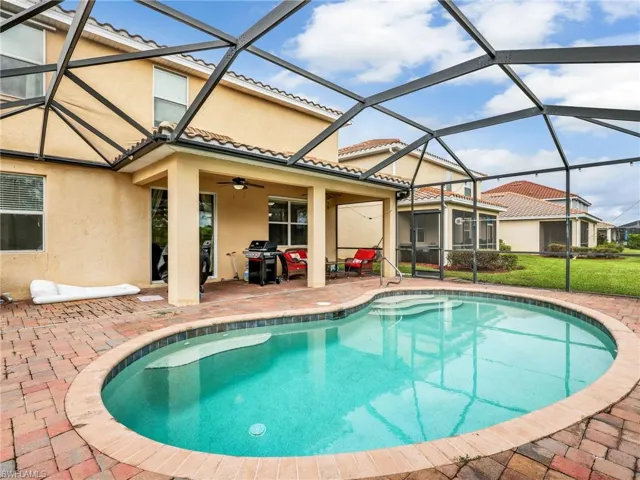 Swimming pool with a sunroom, a patio area, glass enclosure, and area for grilling