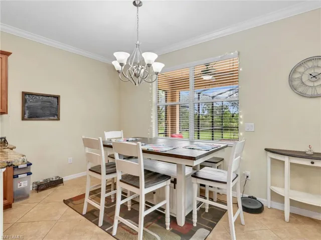 Dining room with ornamental molding, light tile patterned flooring, and a chandelier