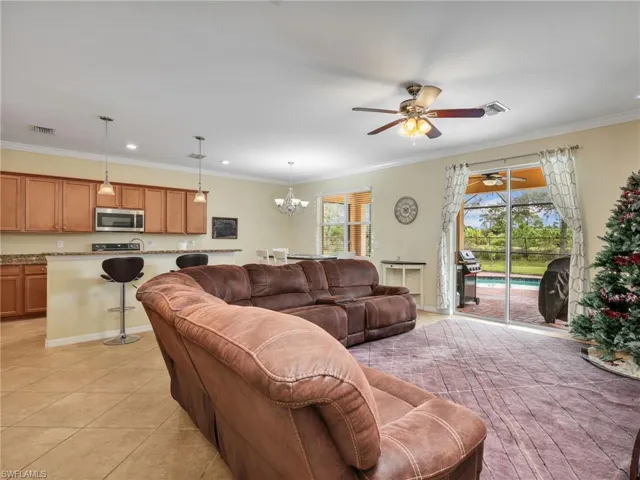 Living area with ornamental molding, a chandelier, light tile patterned floors, ceiling fan, and recessed lighting